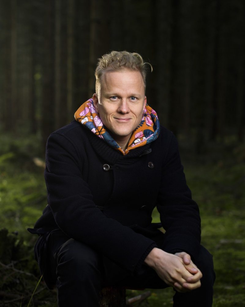 Henrik Ståhl sitting on a stump in a Swedish forest